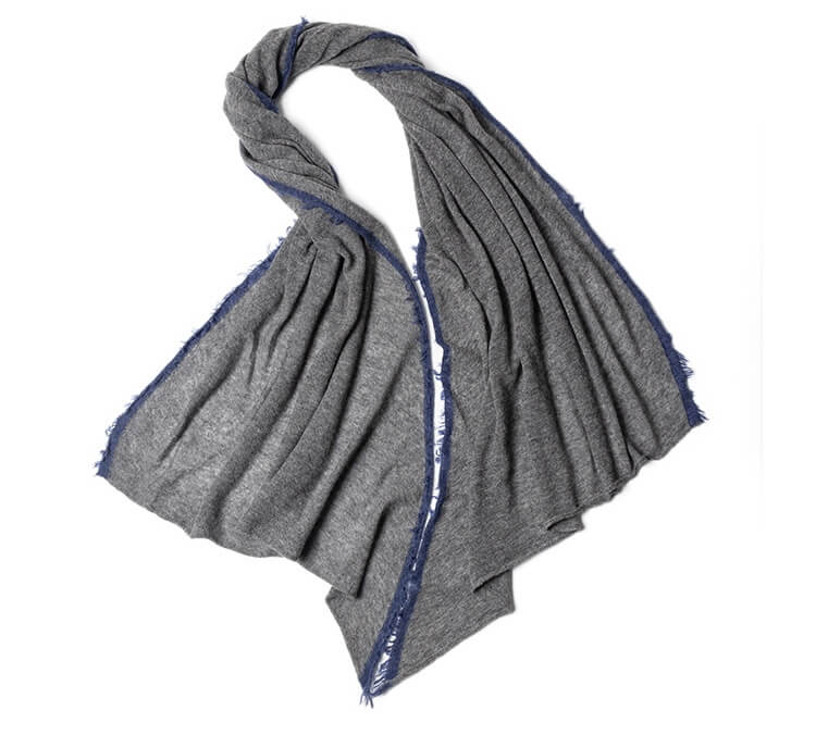 Close-up of Mongolian cashmere yarns and raw fringe details in natural light grey