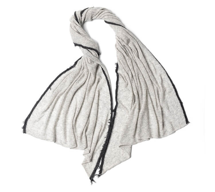 Hand holding 120g cashmere scarf demonstrating airy drape and transparency