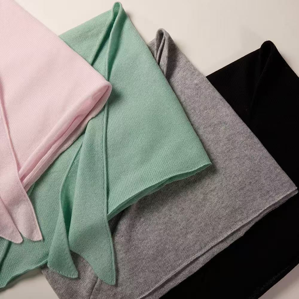 Close-up of fine knit texture of lightweight 100% cashmere triangle scarf in pink, mint, grey and black