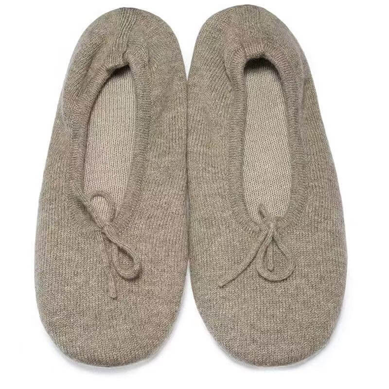 A pair of knit slip-on pure cashmere slippers in a taupe-beige color, featuring a small tie detail on the front