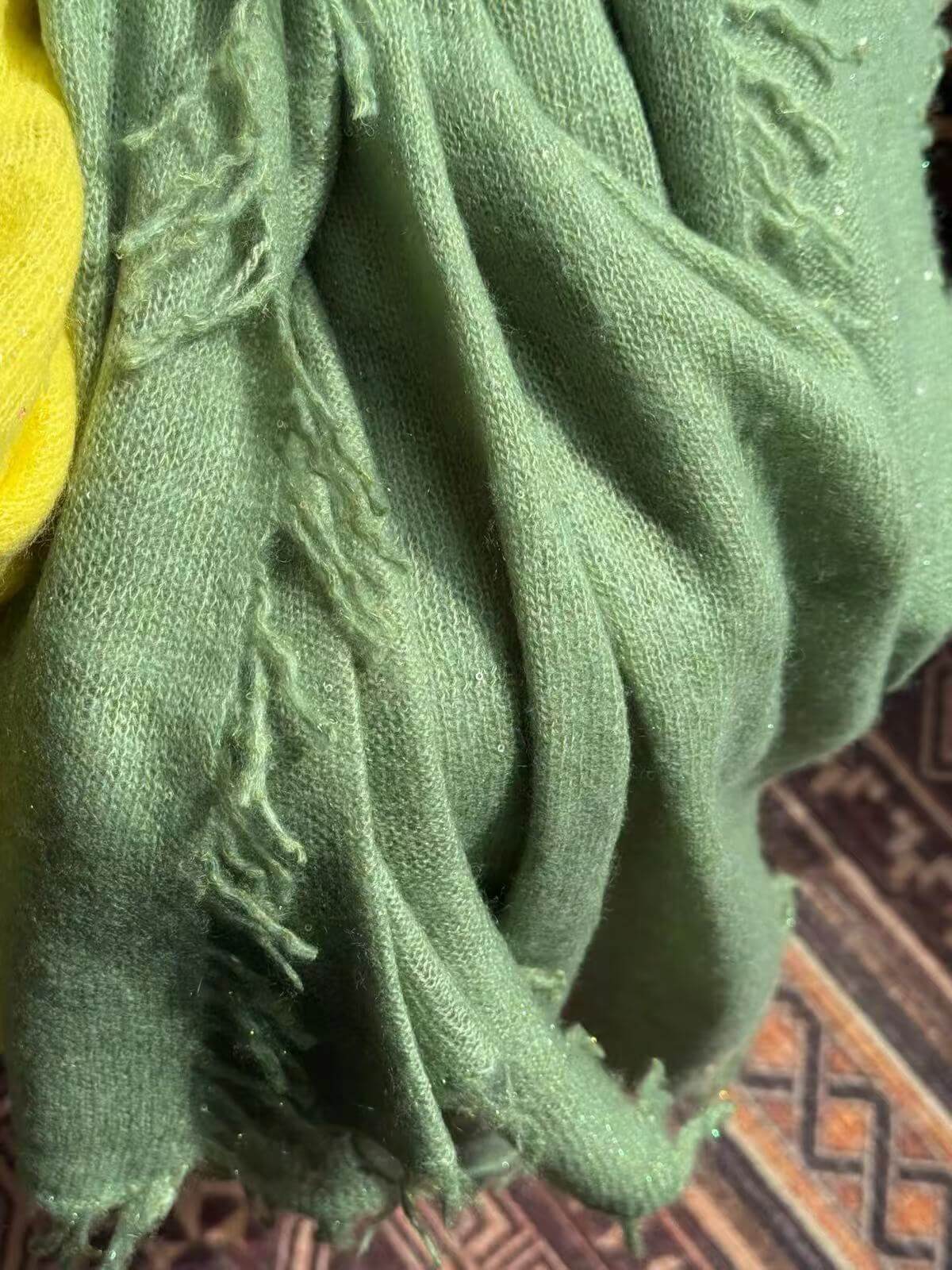 Detailed view of apple green cashmere scarf with delicate sequins, airy fabric and handcrafted twisted fringe.