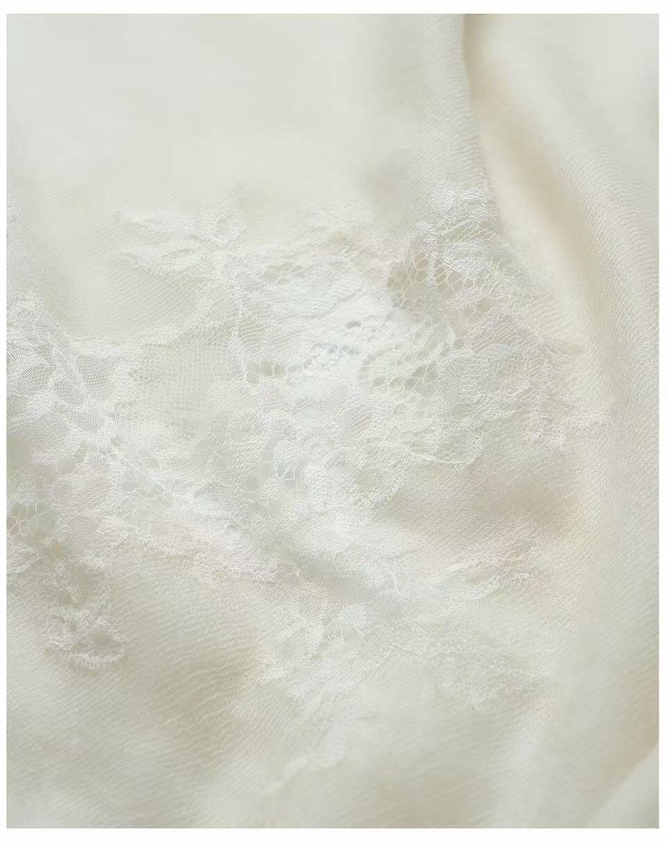 Handmade ivory cashmere lace shawl draped over a wedding dress for a timeless bridal look