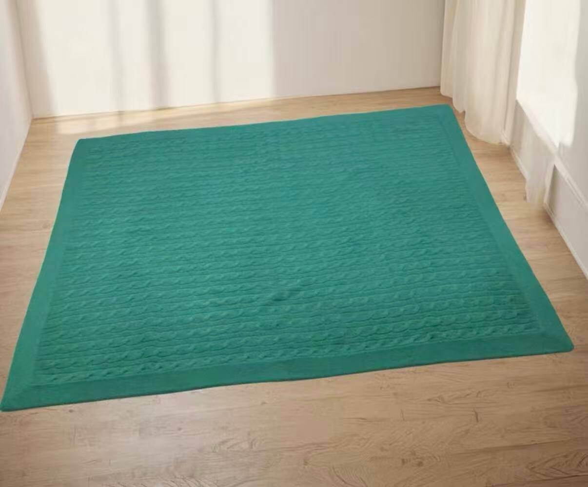 Soft cashmere baby blanket in sage green draped over wooden crib in Scandinavian nursery
