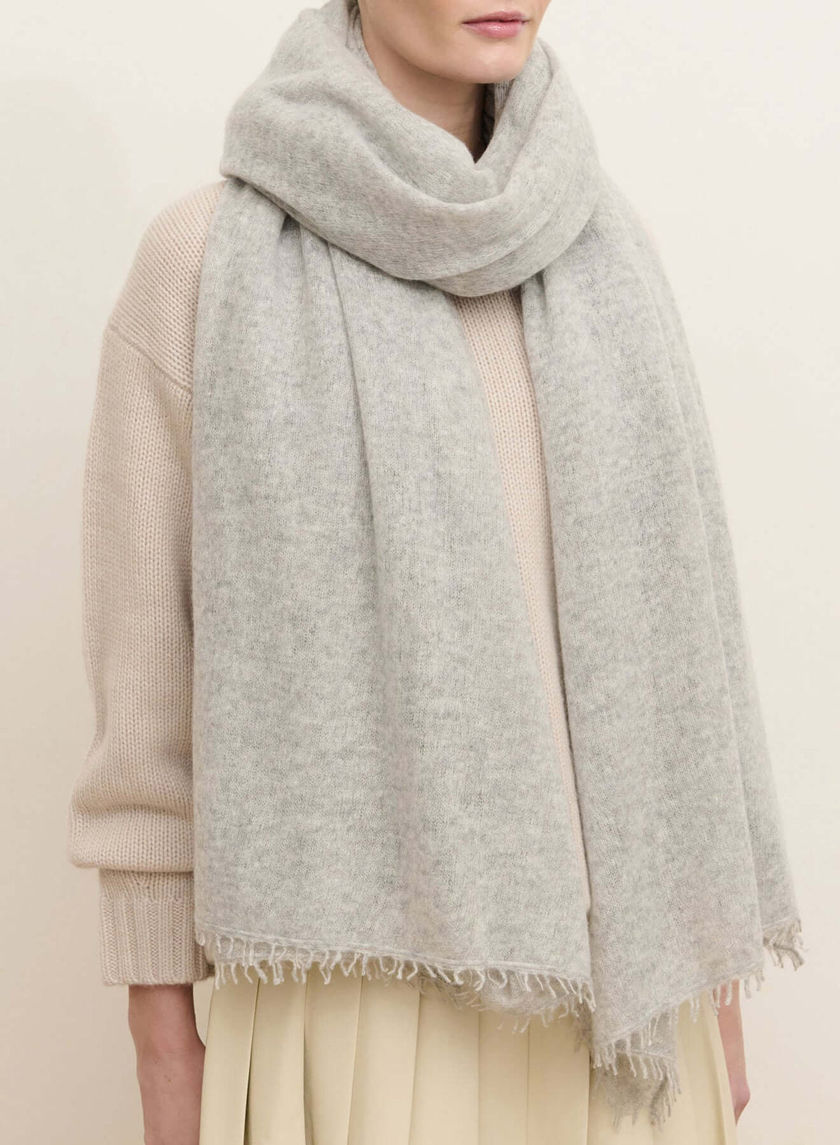 Light heather gray oversized cashmere wrap with fine fabric texture, soft folds, and hand-finished fringe along the edges.