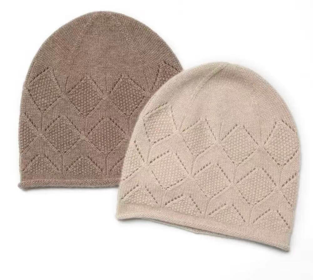 Two cashmere beanies in undyed beige and camel with diamond pointelle knit and rolled edges.