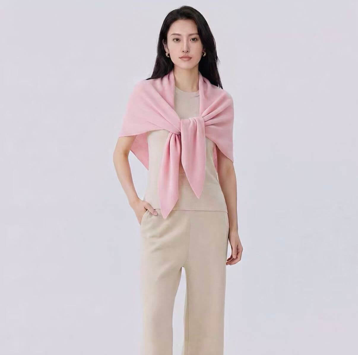 Woman wearing a pink cashmere triangle shawl as a cozy travel wrap for airplane and autumn layering