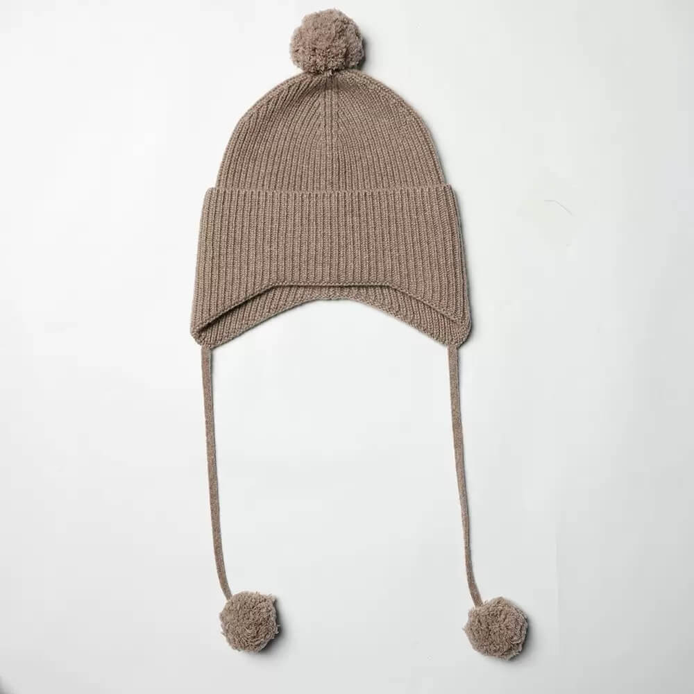 Luxury 100% cashmere pom pom earflap hat in undyed camel color.Ribbed knit detail of luxury 100 percent cashmere earflap hat