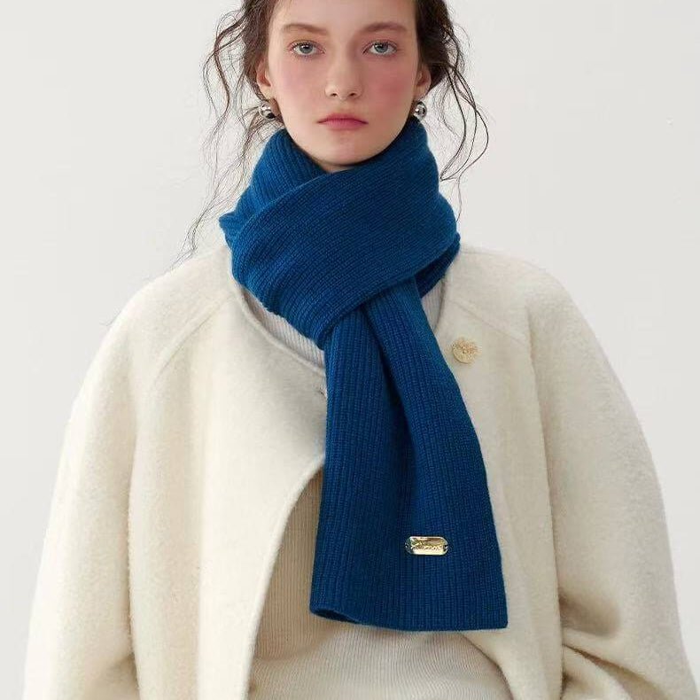 a woman wearing a blue 100% cashmere ribbed scarf and beige coat on a white background