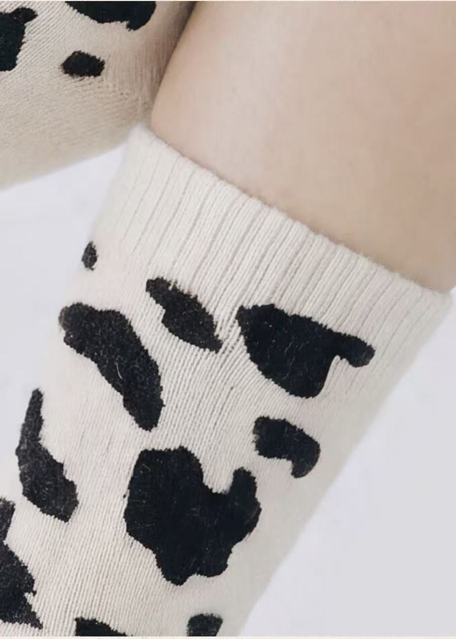 Close-up of ribbed cuff and cow print knit on white cashmere-blend crew socks