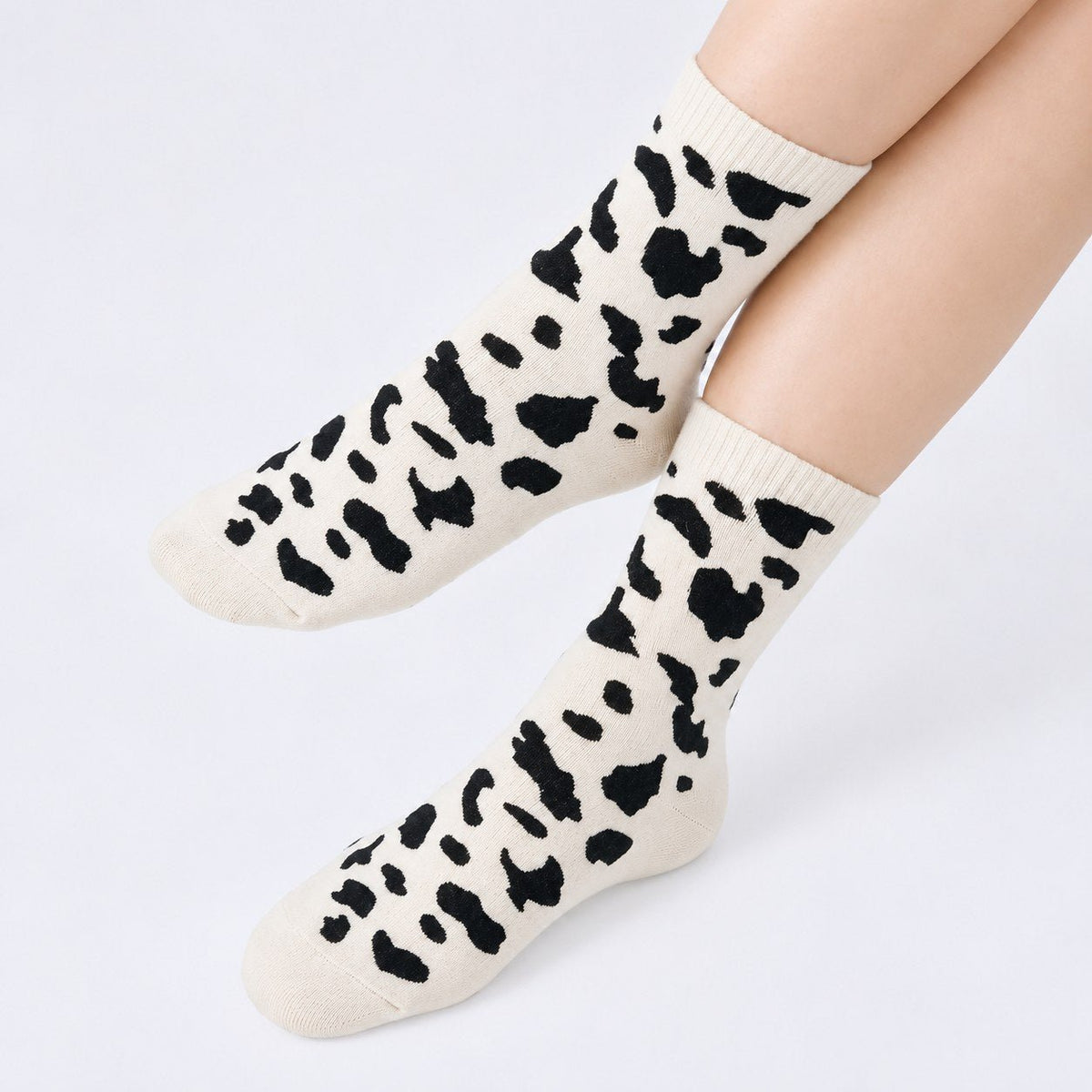 Model wearing white cow print cashmere-blend crew socks, legs crossed