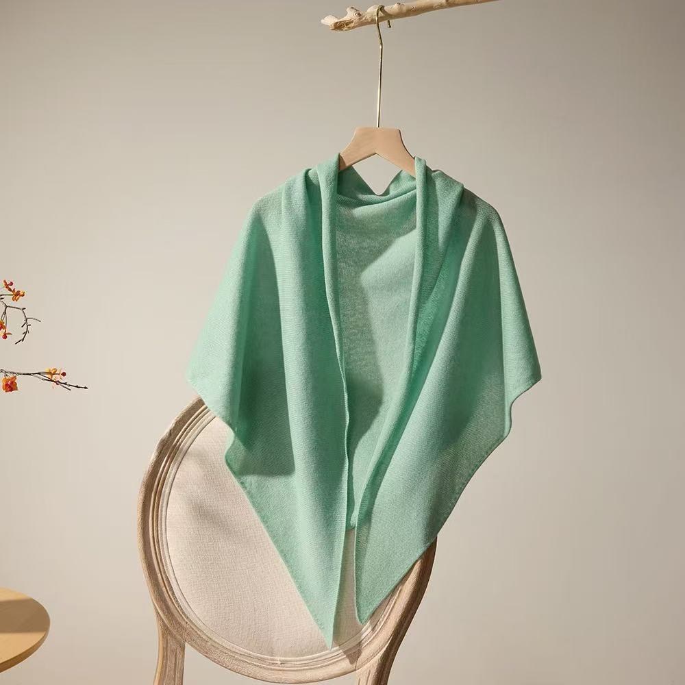 Mint green lightweight 100% cashmere triangle scarf draped over a chair