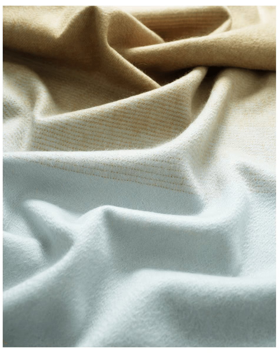 Close-up of ombré cashmere shawl folds, beige blending into soft grey