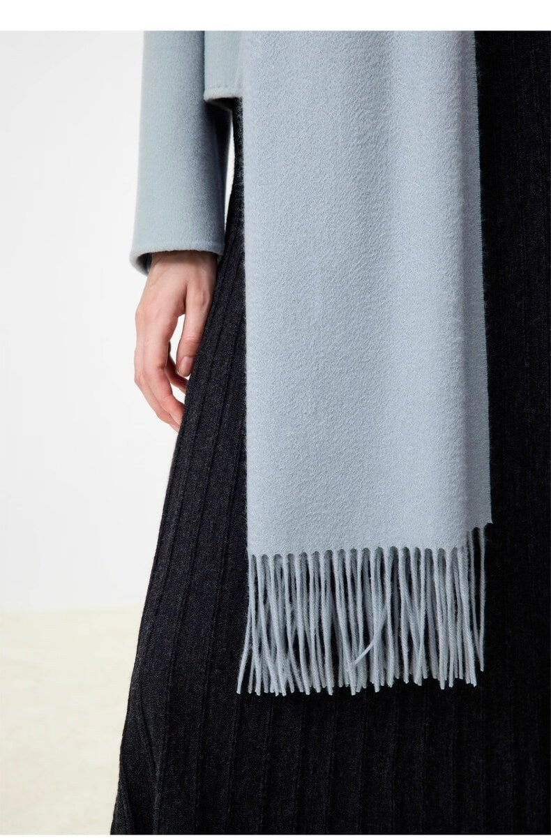 Light blue 100% cashmere scarf with fringes draped over a black garment