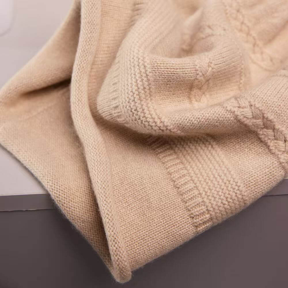 Close-up of a cream-colored knit sweater showing detailed cable and ribbed textures.