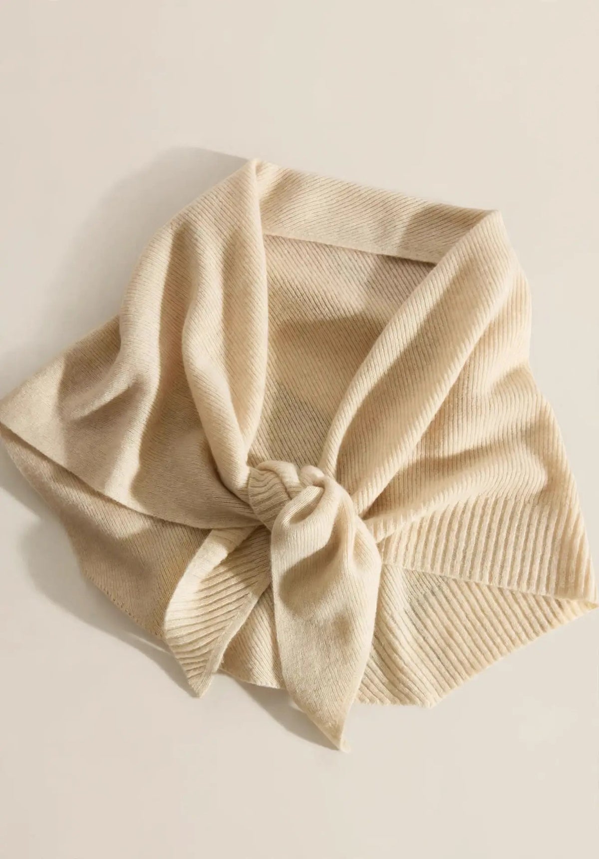 Beige 100% cashmere triangle scarf styled in an elegant knot, flat lay