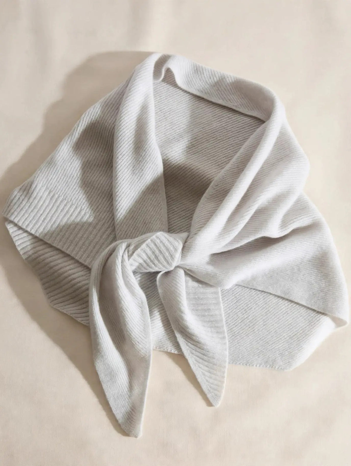 Light mist grey 100% cashmere triangle scarf styled in an elegant knot, flat lay